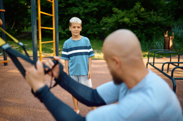 Obraz premium Dad and son doing exercise with ropes, playground