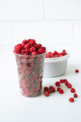 Ripe raspberries in a transparent glass. Ripe raspberries on a white background. Juicy ripe berries.