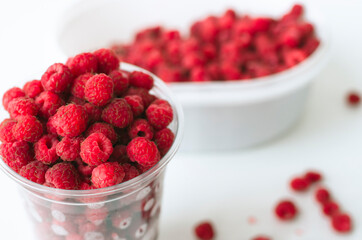 Ripe raspberries in a transparent glass. Ripe raspberries on a white background. Juicy ripe berries.