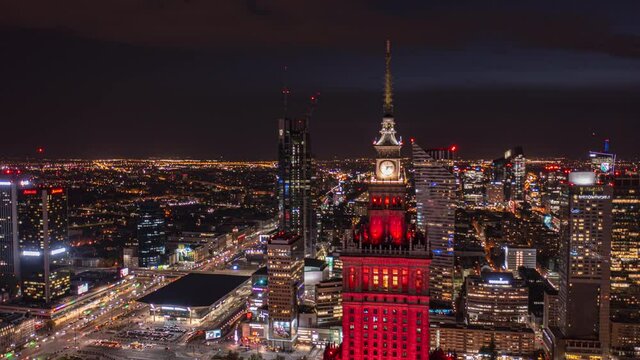 Slide and pan footage of night cityscape. Hyperlapse shot of red illuminated historic high rise Palace of Culture and Science. Warsaw, Poland