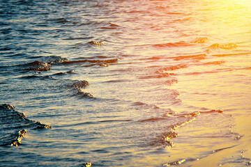 Water surface with small waves. River, lake, pond. Golden rays of sun reflected on surface of water.