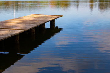Obraz premium Empty pier at a lake and water reflecting the sky with copy space