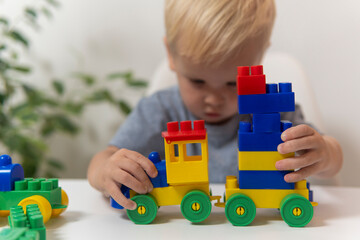 Two year old child playing in his room with a toy train