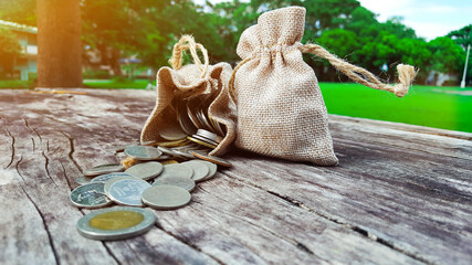 Coin gunnysacks with the sun light, one is down and one is up on wood plank with blur background © KPD