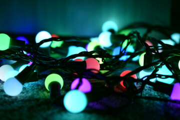 Multicolored lamps of the Christmas tree garland on the carpet