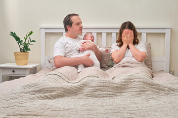 A father with a baby boy and a mother crying in postpartum depression, parents and an infant child...