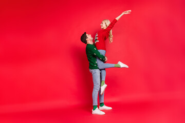 Full length body size photo boyfriend keeping overjoyed happy girlfriend laughing isolated vivid red color background