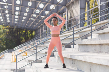 Woman doing burpee exercise, young African American woman doing fitness and active lifestyle in the morning, outdoors near the stadium
