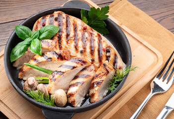 Roasted chicken fillet and mushrooms with herb in the frying pan on the wooden table close-up.