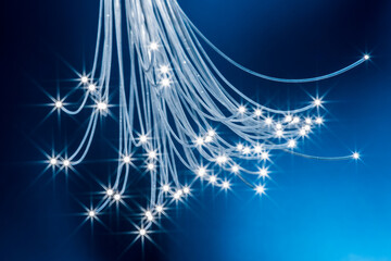 Bundle of optical fibers with lights in the ends. Blue background.