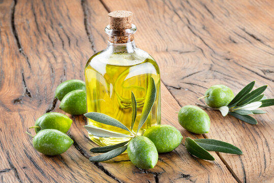 Green natural olives with bottle of olive oil on a vintage old wooden table.