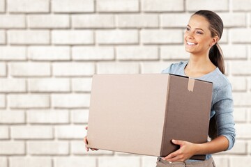 Smiling woman moving to new apartment, standing together over wall with big paper boxes