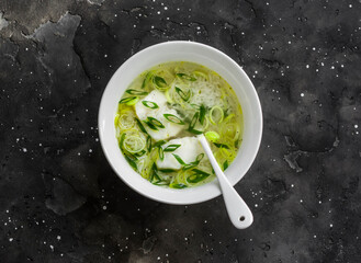 Cod, leek and rice broth on a dark background, top view. Delicious soup for lunch