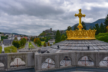 Fototapeta na wymiar Lourdes, France - 9 Oct 2021: Gold gilded cross atop the dome of the Basilica of Our Lady of the Rosary in Lourdes
