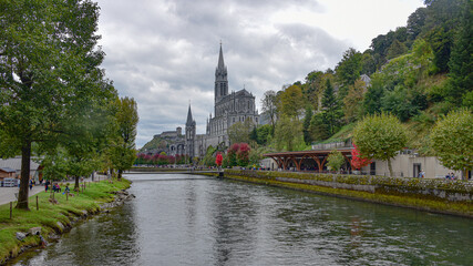 Fototapeta na wymiar Lourdes, France - 9 Oct 2021: Views of the Rosary Basilica Church from the Gave de Pau river in Lourdes