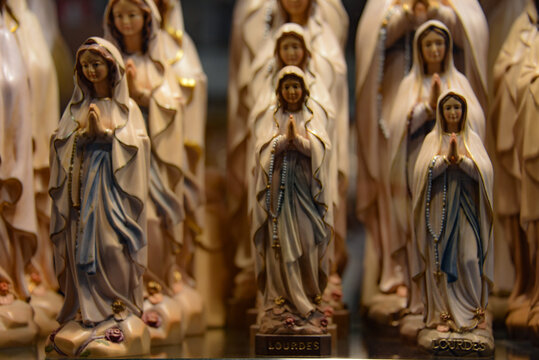 Lourdes, France - 9 Oct 2021: Figurine statues of the Virgin Mary on sale at a tourist souvenir shop in Lourdes, France