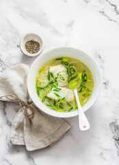 Cod, leek and rice broth on a light marble background, top view. Delicious diet soup for lunch