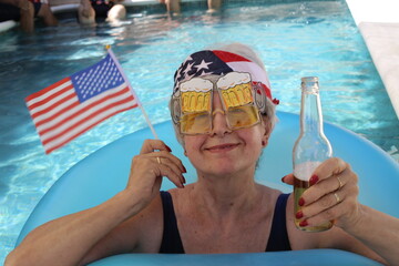 Mature woman celebrating an American holiday with a beer in a pool