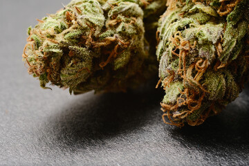 Close up of cannabis buds, macro view. Medicinal marijuana flowering with trichomes on black paper...