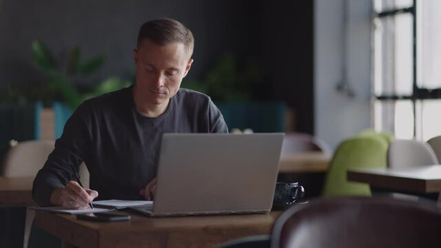 Smiling man with works from home in his kitchen using a laptop. Remote work and remote learning. remote work during self-isolation in quarantine, man works with financial documents.