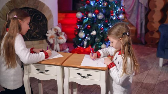 Little girls during Christmas time. Happy little girls drawing picture for Santa Claus