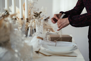 Unrecognizable Woman Hosting Elegant Dinner Party and Making Christmas Present. 

Close up photo of...