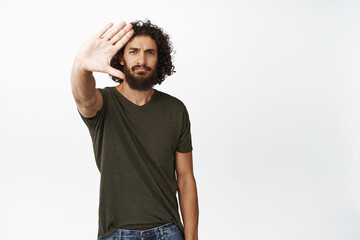 Sassy young man stretch out hand in stop gesture, saying no, rejecting something, prohibit action,...