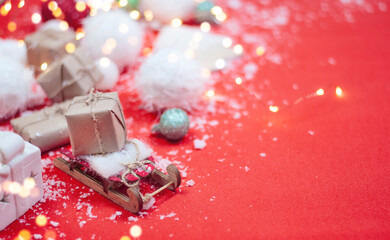 christmas background with wooden sled, presents and toys on the red table with copy space