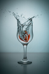 A strawberry dropped into a glass of water