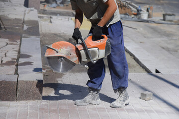 A worker holds a circular saw on a construction site.