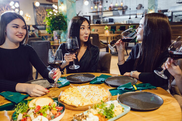 A group of women friends chatting and drinking wine in a restaurant.