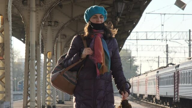Young Female in Warm Coat with Umbrella in Hands and Backpack Walking Along Railway Platform in Sunny Autumn Day. Slow Motion. New Normal, Journey, Trip, Travel by Train Concept