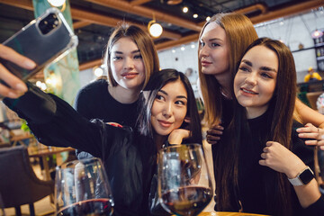 A group of girlfriends take a selfie at dinner in a restaurant.