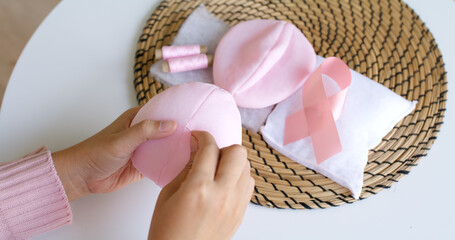 Close-up hand asia woman help make craft pink single fill up bra cup insert for post mastectomy...