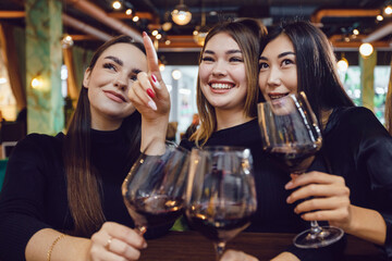 Four beautiful women are drinking wine in a restaurant.
