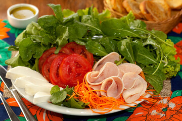 Salada deliciosa com folhas verdes, tomates, queijo fresco, cenoura e fatias de peito de peru em...