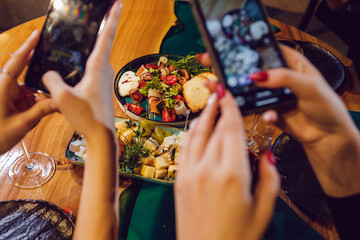 Girls take pictures of dinner in a restaurant.