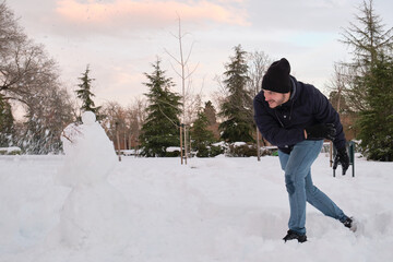 Fototapeta na wymiar Young caucasian man destroying a snowman