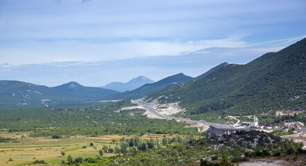 Krajobraz górski panorama z drogą ciągnącą się wzdłuż zbocza gór - obrazy, fototapety, plakaty