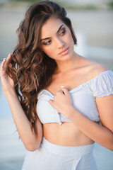 A gorgeous young girl relaxes on the beach in the sunset light