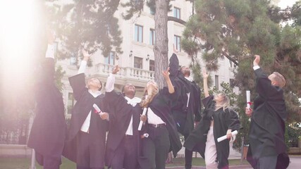 Very happy and excited group of attractive and beautiful ladies and guys after the graduation throw up the graduation caps and hugging excited all together