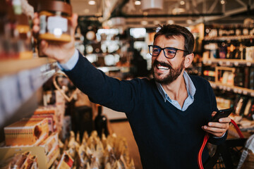 Handsome middle age man buying some healthy food and drink in modern supermarket or grocery store. Lifestyle and consumerism concept.