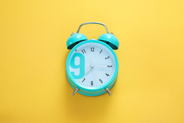 Blue alarm clock on the yellow background. Morning, time to wake up. Free space, copy space.