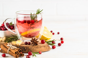 Cranberry tea with lemon and spices at white table. Healthy hot drink.