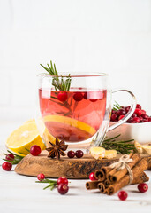 Cranberry tea with lemon and spices at white table. Healthy hot drink.