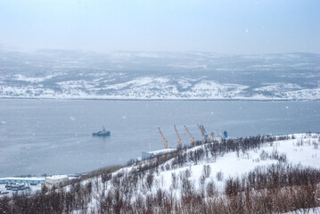 Harsh north. Winter landscape. Snow flakes cover the hills of the Kola Peninsula and the water of the Kola Bay. Murmansk.