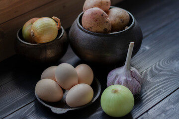 eggs potatoes garlic and onion on the wooden table