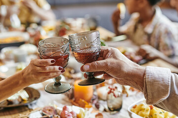 Close-up of senior couple toasting with glasses with red wine while sitting at dining table with family