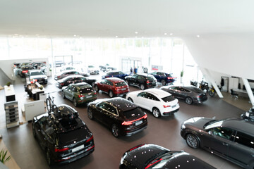Blurred background of new cars displayed in luxury showroom, panorama