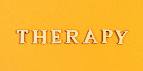Word therapy made from wooden letters on orange positive color background.